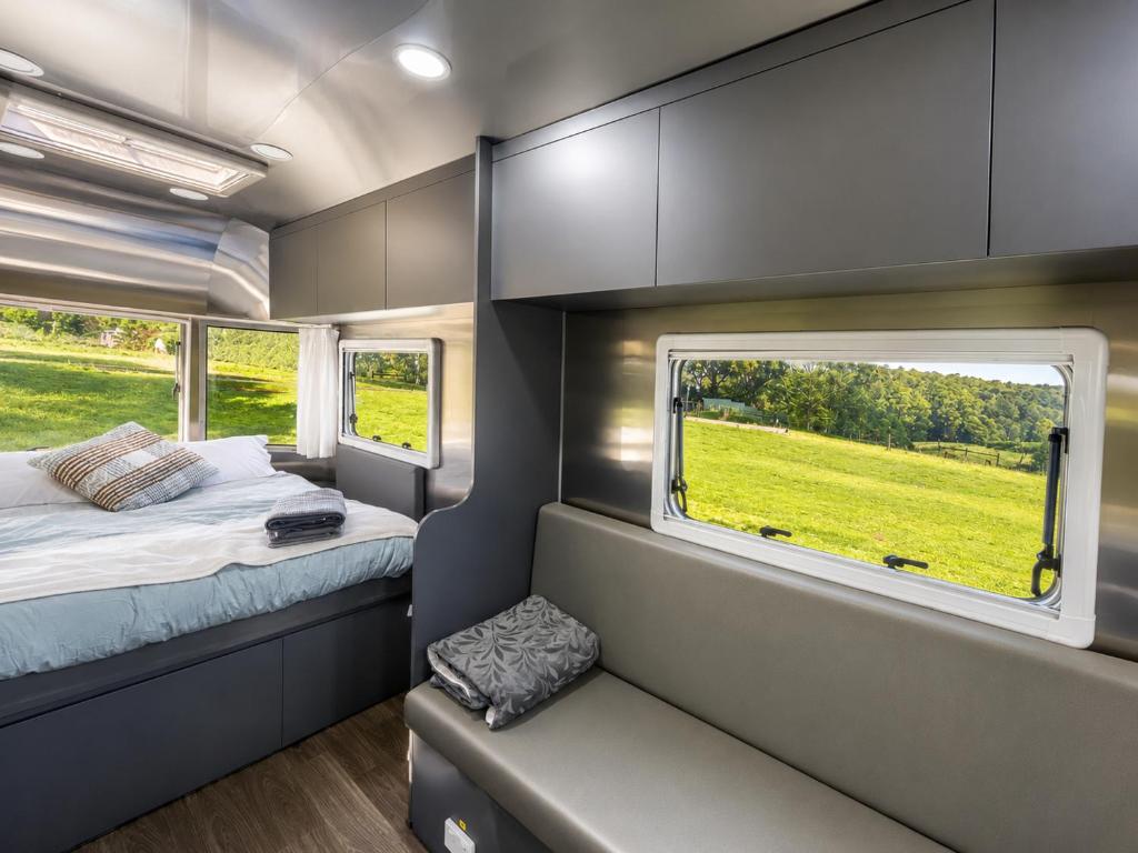 a small bedroom with a bed and a window at One Life Glamping Caravan Rawson in Rawson