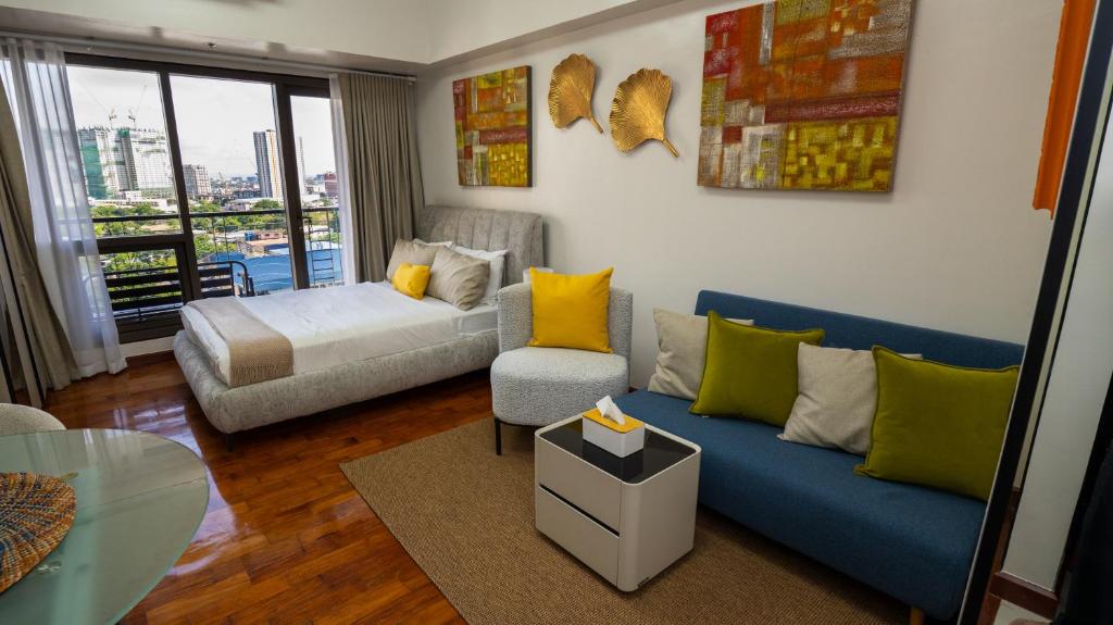 a living room with a blue couch and a bed at The Mosaic Tower Luxury Boutique Studio,Pool and Gym Fast Wifi in Manila