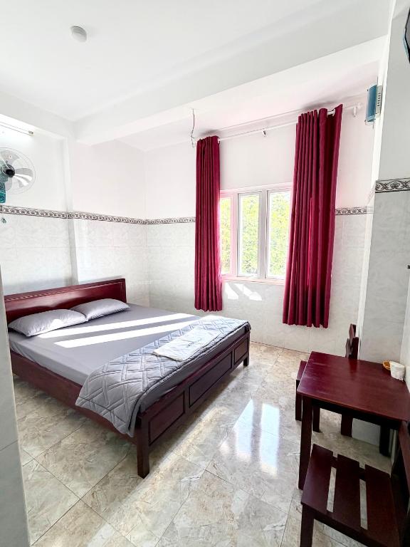 a bedroom with a large bed with red curtains at Nhà Nghỉ Hoa Lan2 in Buon Ma Thuot