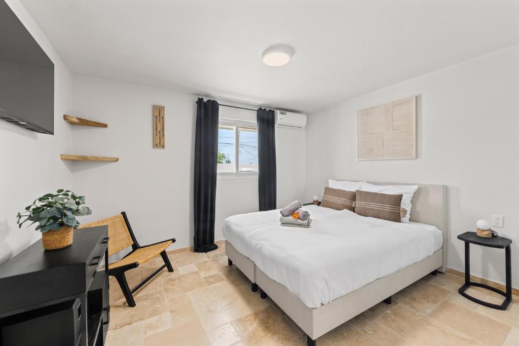 a white bedroom with a bed and a television at Caribe CBW in Willemstad