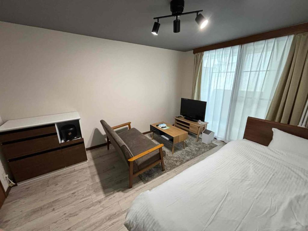 a bedroom with a bed and a desk and a tv at リバーレインアクア in Kagoshima