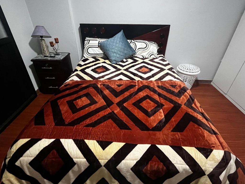 ein Schlafzimmer mit einem Bett mit einer schwarz-weißen Decke in der Unterkunft Departamentos en Cuenca in Cuenca