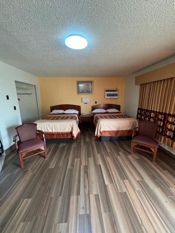 a hotel room with two beds and two chairs at Snowbird Motel in Bristol