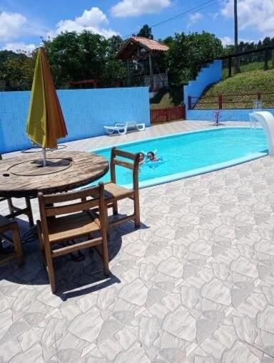 a pool with a table and a yellow umbrella at Sítio Santo Expedito in Salesópolis