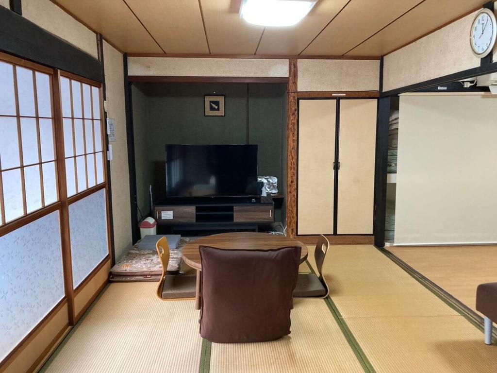 a living room with a table and a large screen tv at 陽だまりハウス in Hiroshima