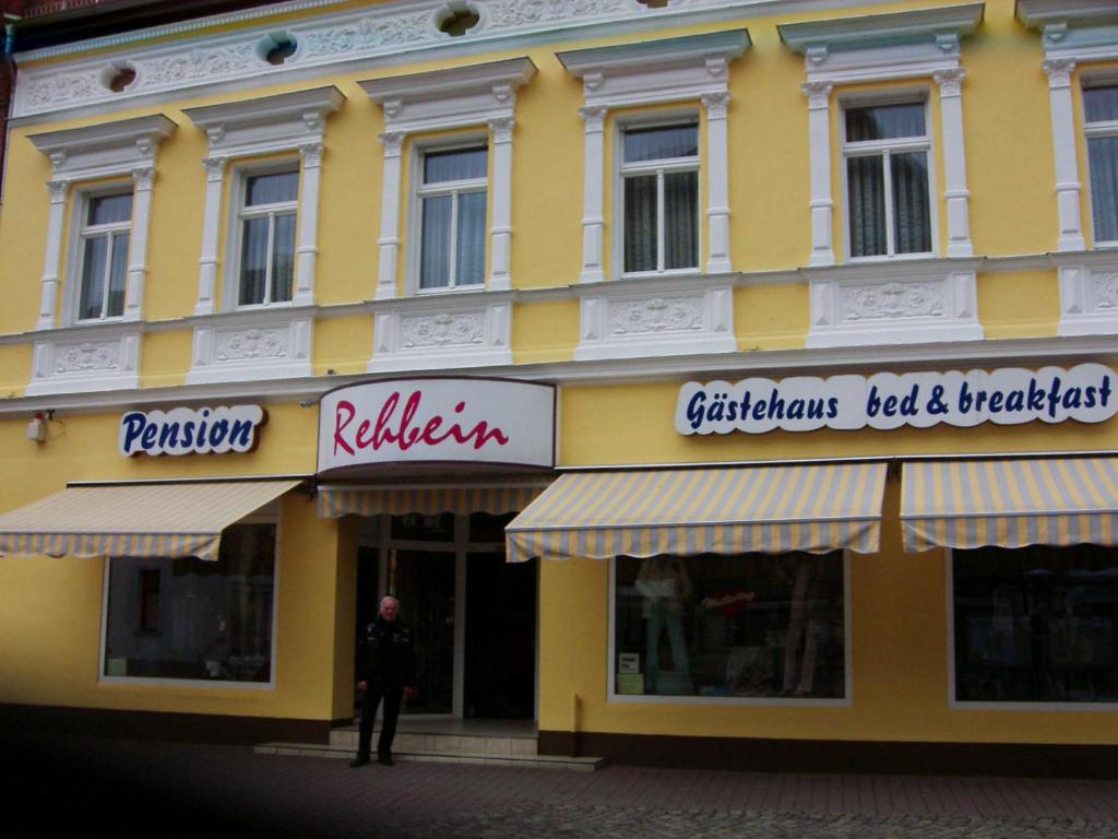 Gaestehaus Rehbein في Calbe: رجل واقف امام مبنى اصفر