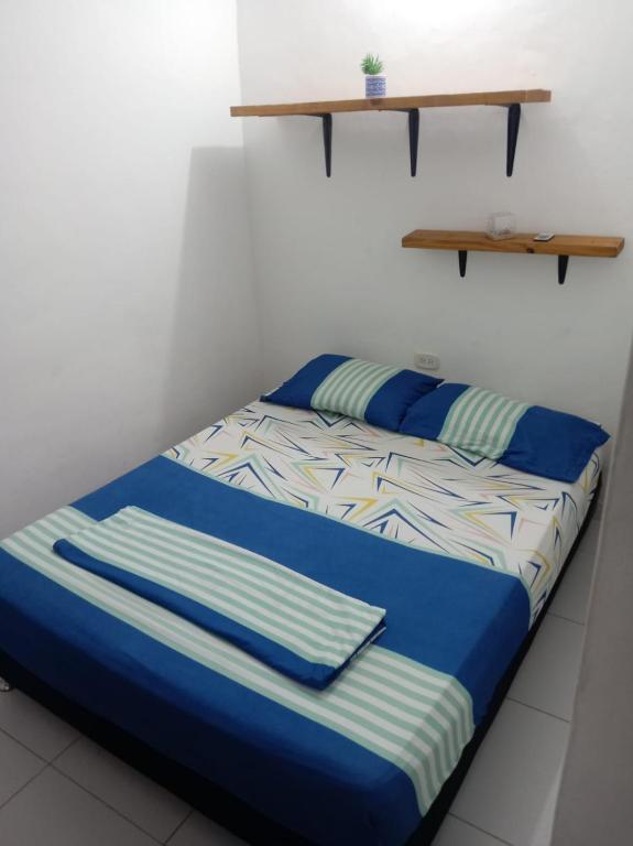 a bed with blue and white sheets and a shelf at Squid Hostel in Santa Marta