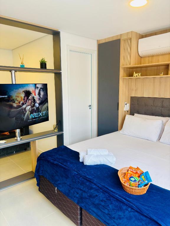 a bedroom with a bed and a flat screen tv at Studio 112 Luxuoso Cama Queen Ar Condicionado e Cozinha Completa in Mogi das Cruzes