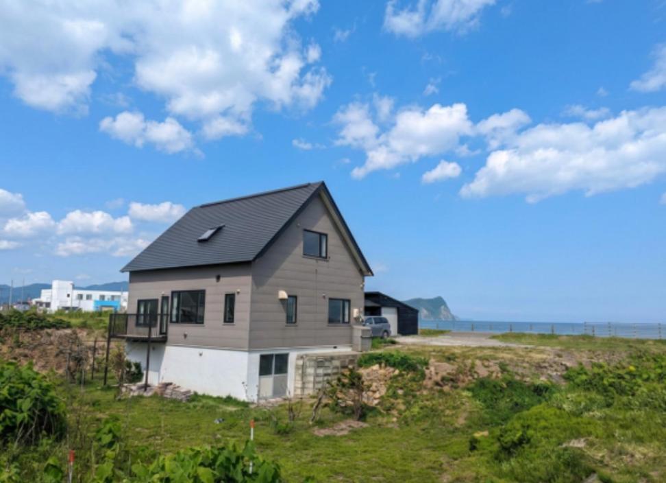 a house sitting on top of a grass field at Fugoppe Beachfront Villa in Yoichi