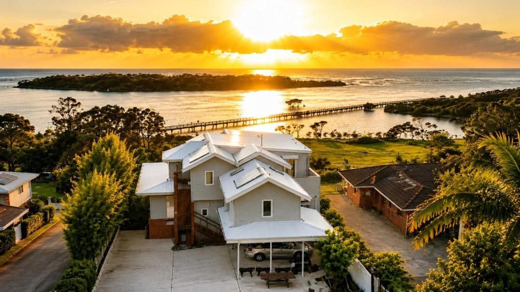 a house with the sunset in the background at Urunga Magic. in Urunga