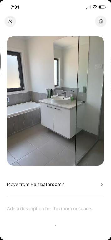 a bathroom with a tub and a sink and a mirror at Guinevere2 in Myrtleford