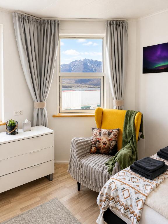 a bedroom with a bed and a window and a chair at Aurora Apartament in Borgarnes