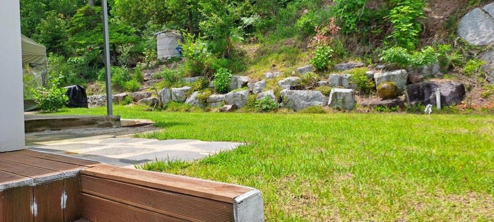 a yard with a field of green grass and rocks at Boseong Deukryangman Pension in Boseong