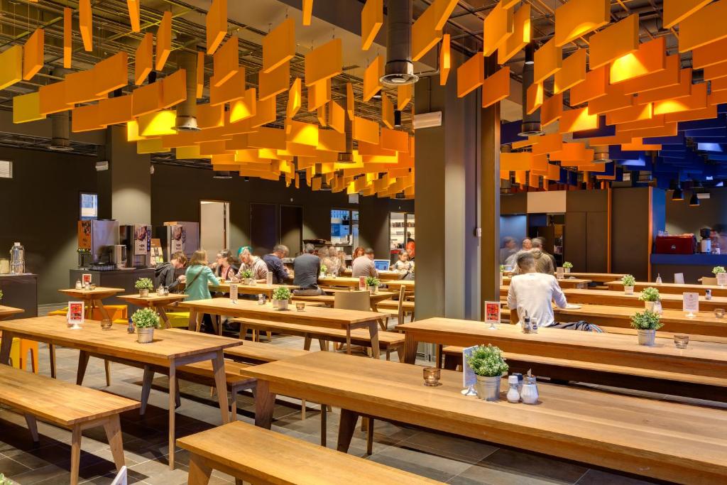 a restaurant with wooden tables and people in the background at MEININGER Hotel Amsterdam City West in Amsterdam