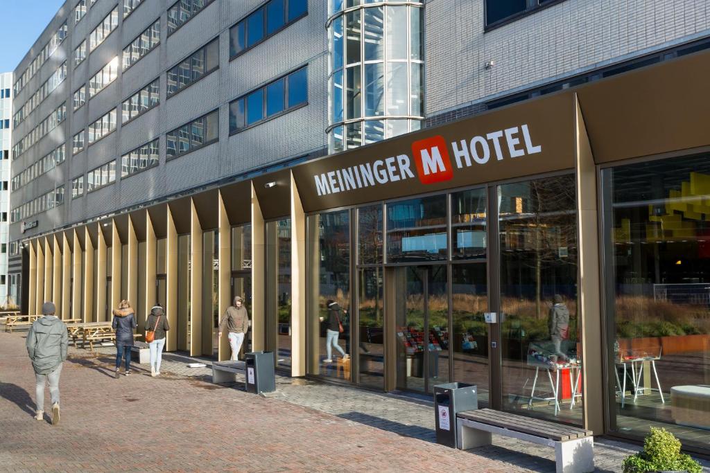 a group of people walking outside of a building at MEININGER Hotel Amsterdam City West in Amsterdam