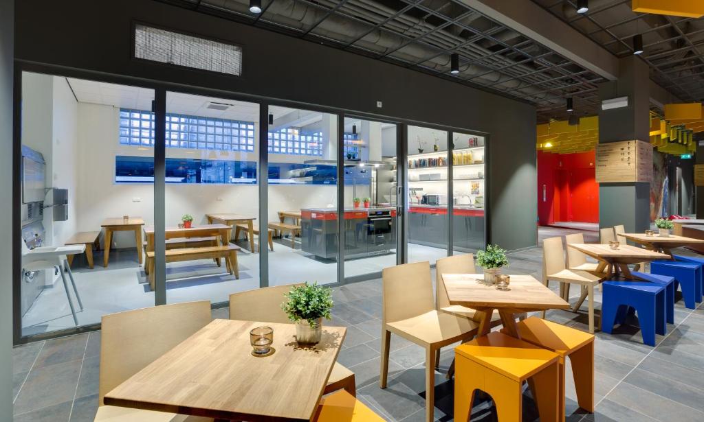 a restaurant with tables and chairs and large windows at MEININGER Hotel Amsterdam City West in Amsterdam