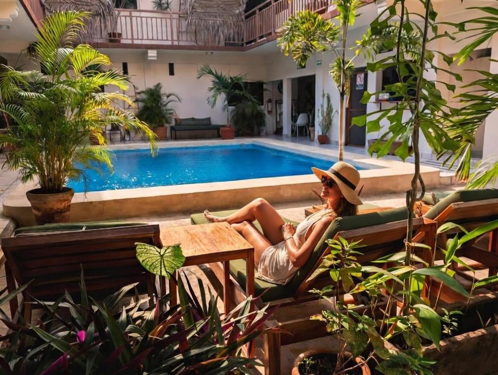 a woman sitting on a bench in front of a pool at Sunset Suites in Brisas de Zicatela