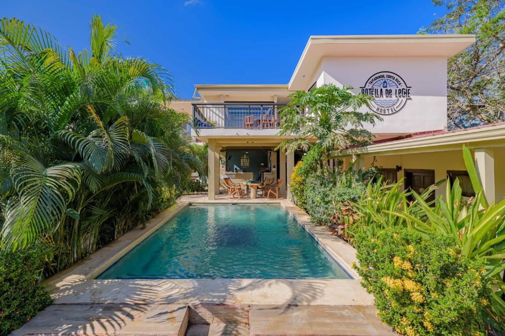 a villa with a swimming pool in front of a house at Hostel La Botella de Leche - Tamarindo in Tamarindo