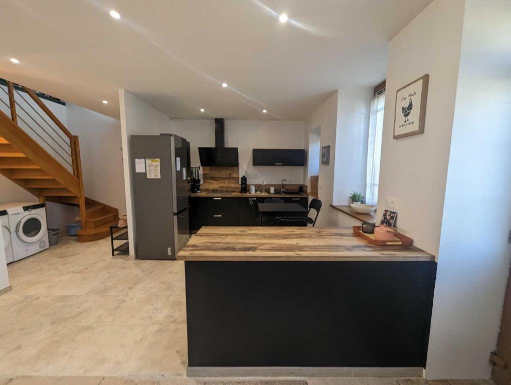 a large room with a kitchen with a refrigerator at L'ecole buissonnière in Riaucourt