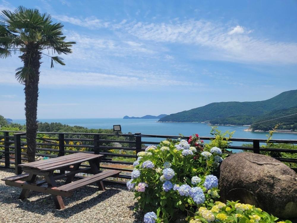 ein hölzerner Picknicktisch, eine Palme und Blumen in der Unterkunft Midae Oppa in Geoje