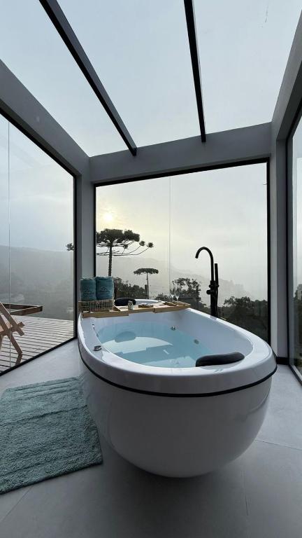 a large bath tub in a room with large windows at Altos do Perito Cabanas in Alfredo Wagner