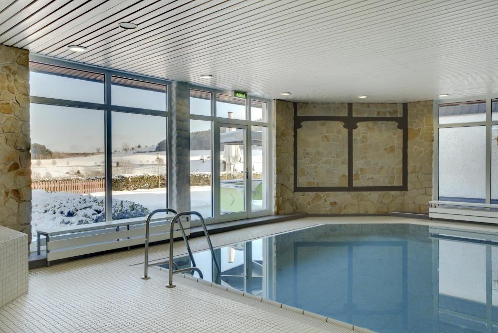 ein großes Schwimmbad in einem Gebäude mit Fenstern in der Unterkunft H+ Hotel Willingen in Willingen