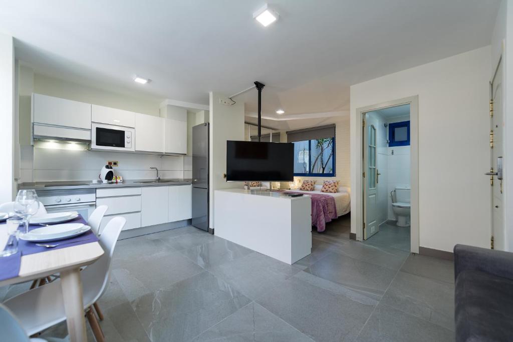 a kitchen with white cabinets and a table with chairs at Suites Garden Apartamento 11 in Las Palmas de Gran Canaria