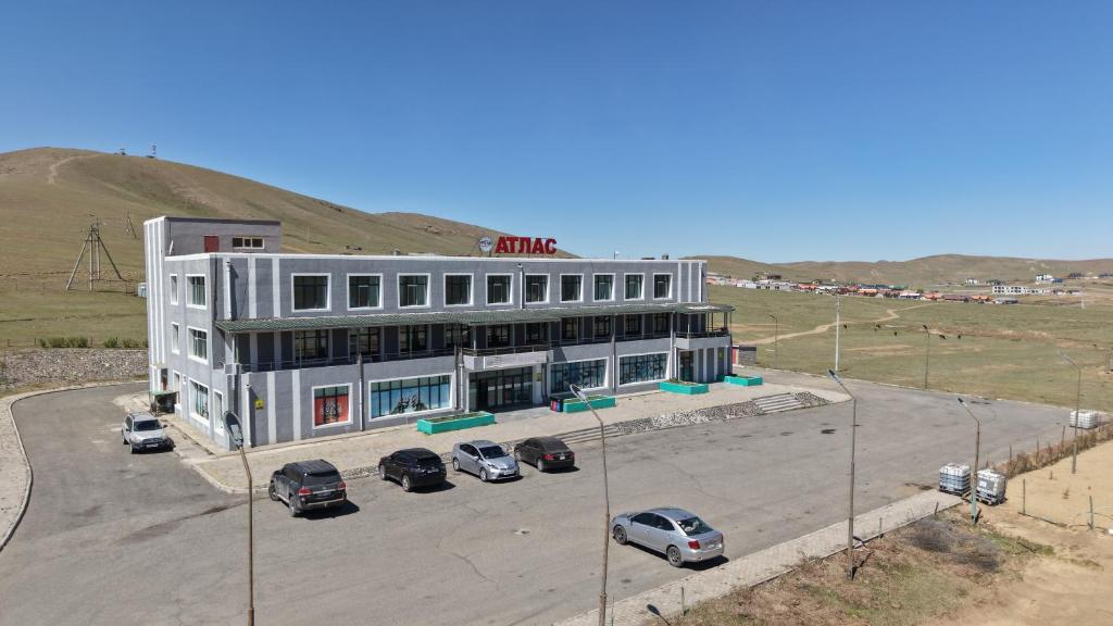 a white building with cars parked in a parking lot at Atlas Hotel in Ulaanbaatar