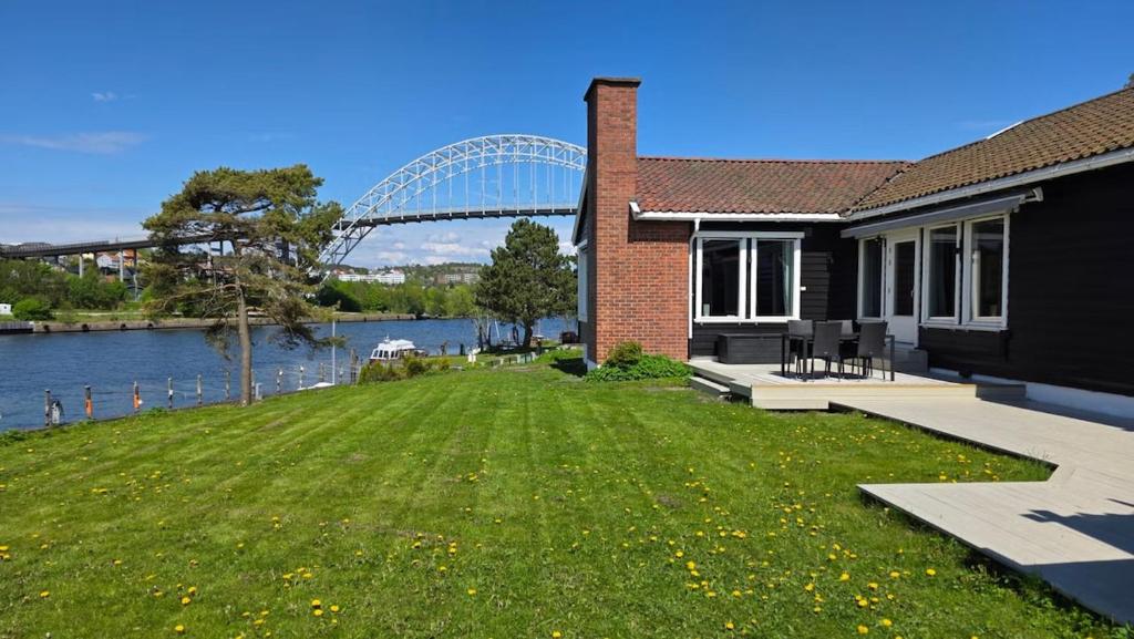 a house with a green yard next to a river at Prestelandet Guesthouse in Fredrikstad