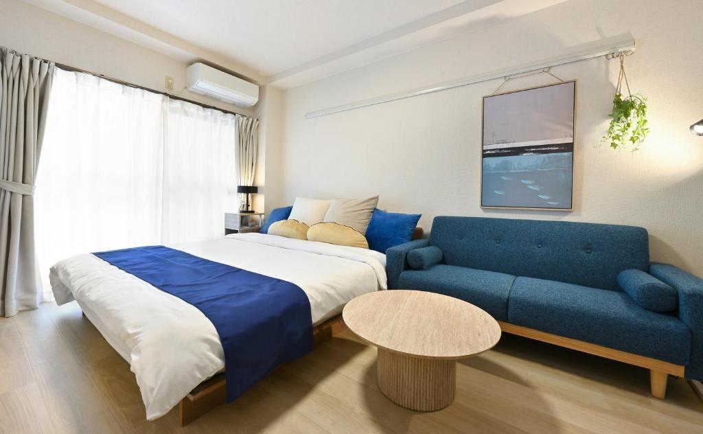 a bedroom with a bed and a blue couch at Haniwa Stay Josai in Nagoya