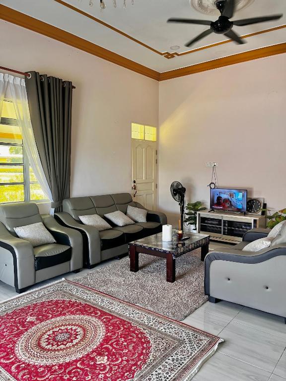 a living room with couches and a tv at Ramly Homestay in Kuala Terengganu