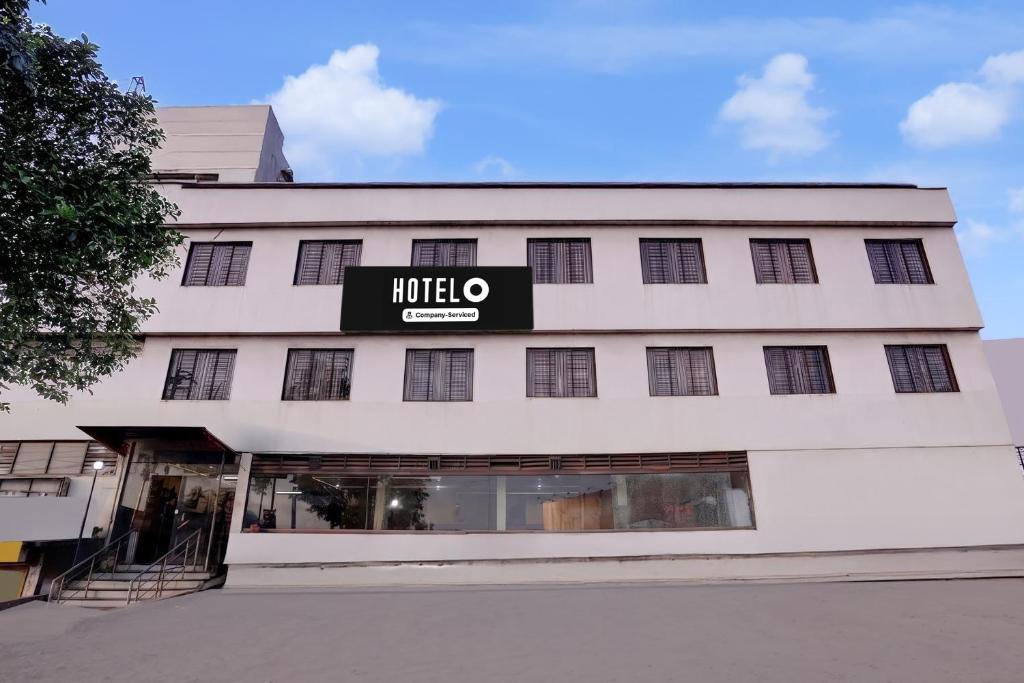a large white building with a mocho sign on it at Hotel O Kolhapur Gate Formerly Tanwani Lodging in Unchagao