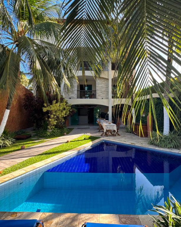 a pool in front of a house with palm trees at Pousada Unaí in Porto De Galinhas
