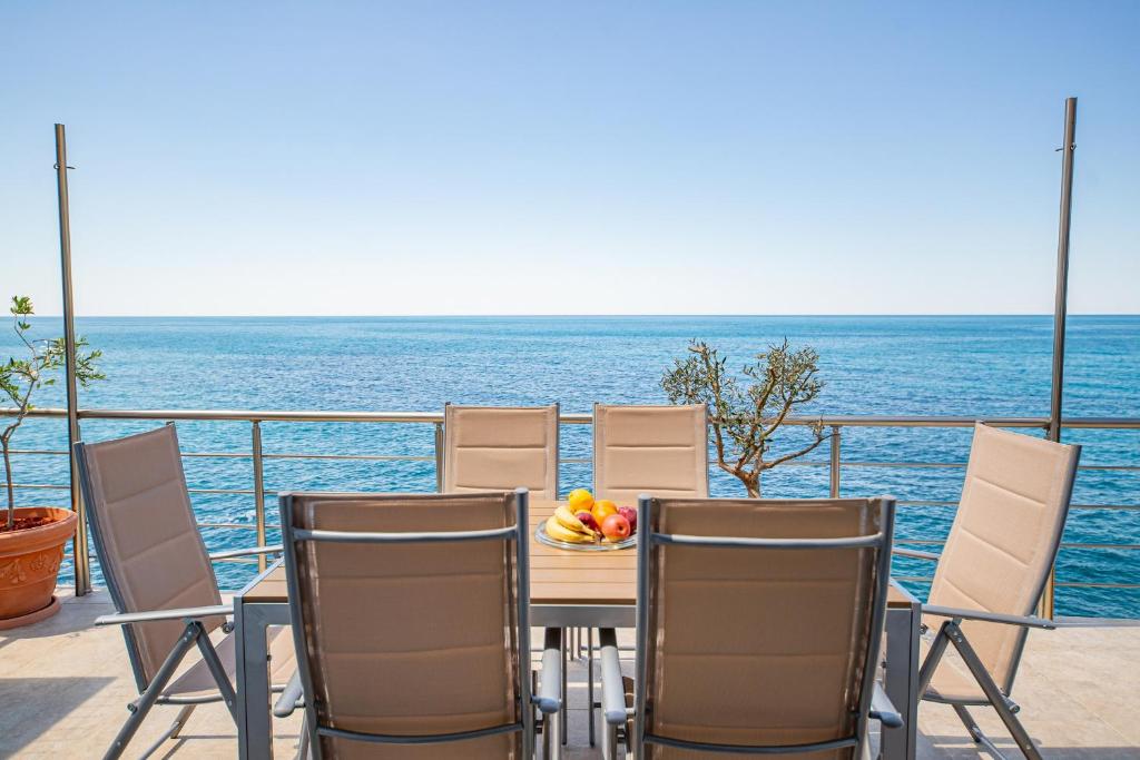 a table and chairs with a bowl of fruit on a balcony at Perfect Seaview Two-bedroom Apartment Tramontana in Dobra Voda