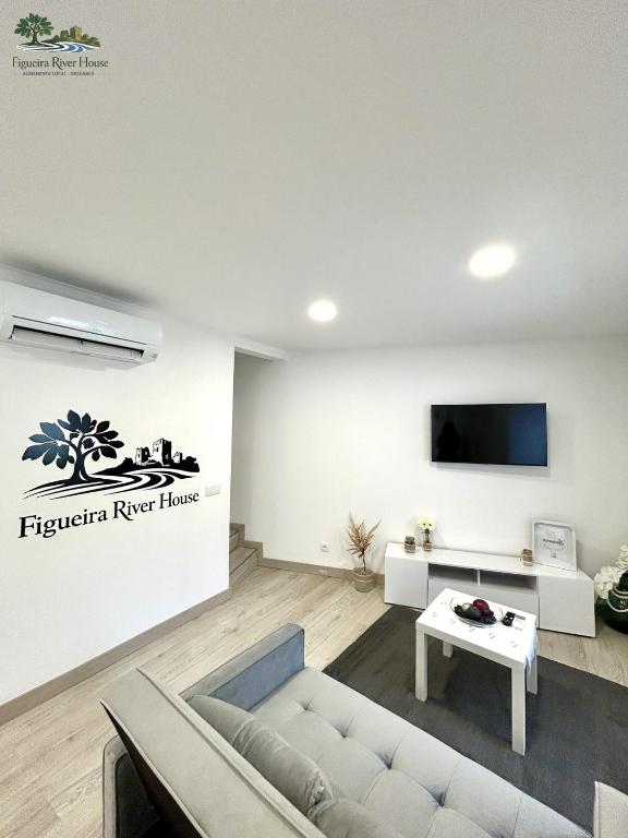 a living room with a couch and a tv on a wall at Figueira River House in Bragança