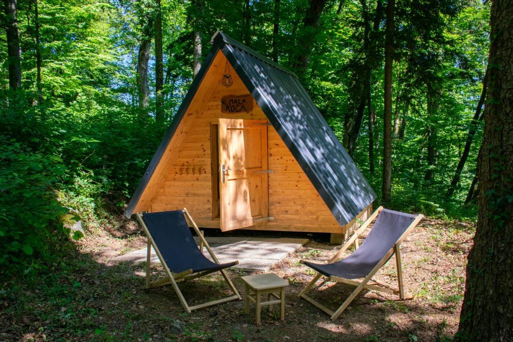 a cabin with two chairs and a tent in the woods at Glamping Zeleni raj Vače in Vače