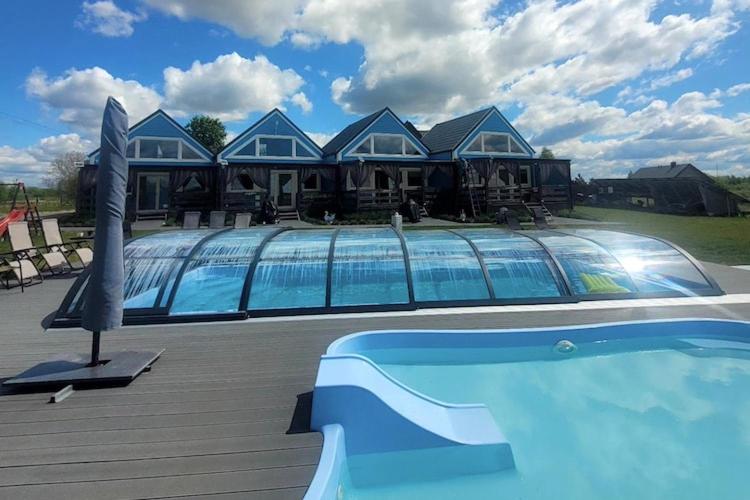 a house with a swimming pool in front of a house at Comfortable holiday home, pool, sauna, jacuzzi in Brzuze