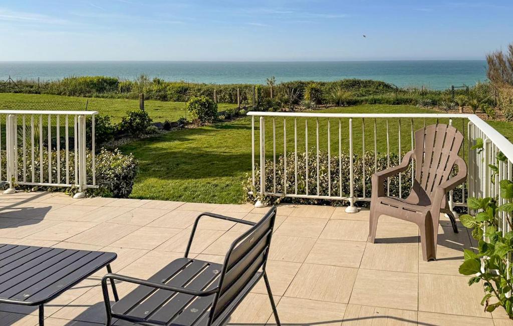 two chairs and a table on a patio with the ocean at Maison Vue Mer in Quiberville