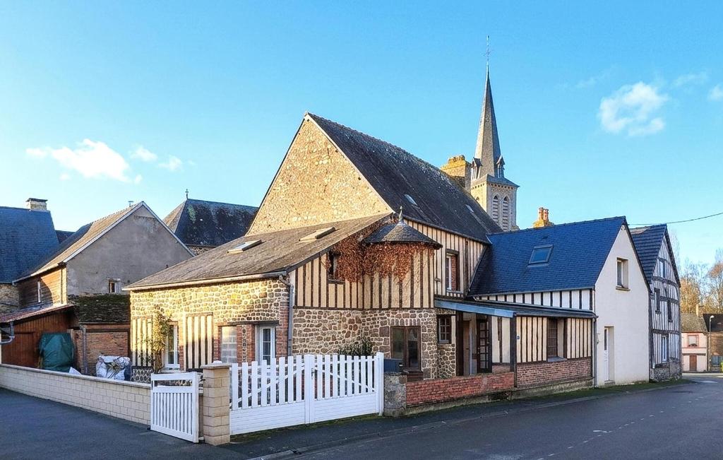 a building with a church with a white fence at Belle Maison À Colombages in La Baroche-sous-Lucé