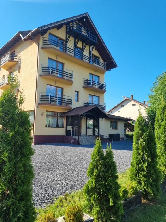 a large apartment building with a gravel driveway at Pensiunea Riffelt in Bran