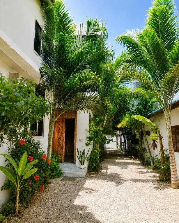 a courtyard with palm trees and a building at Tamu House Paje in Paje