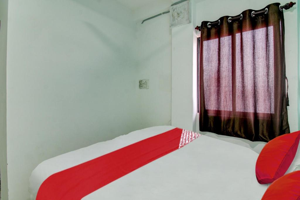 a bedroom with a bed and a red curtain at Hotel O Kings in Pānchgaon