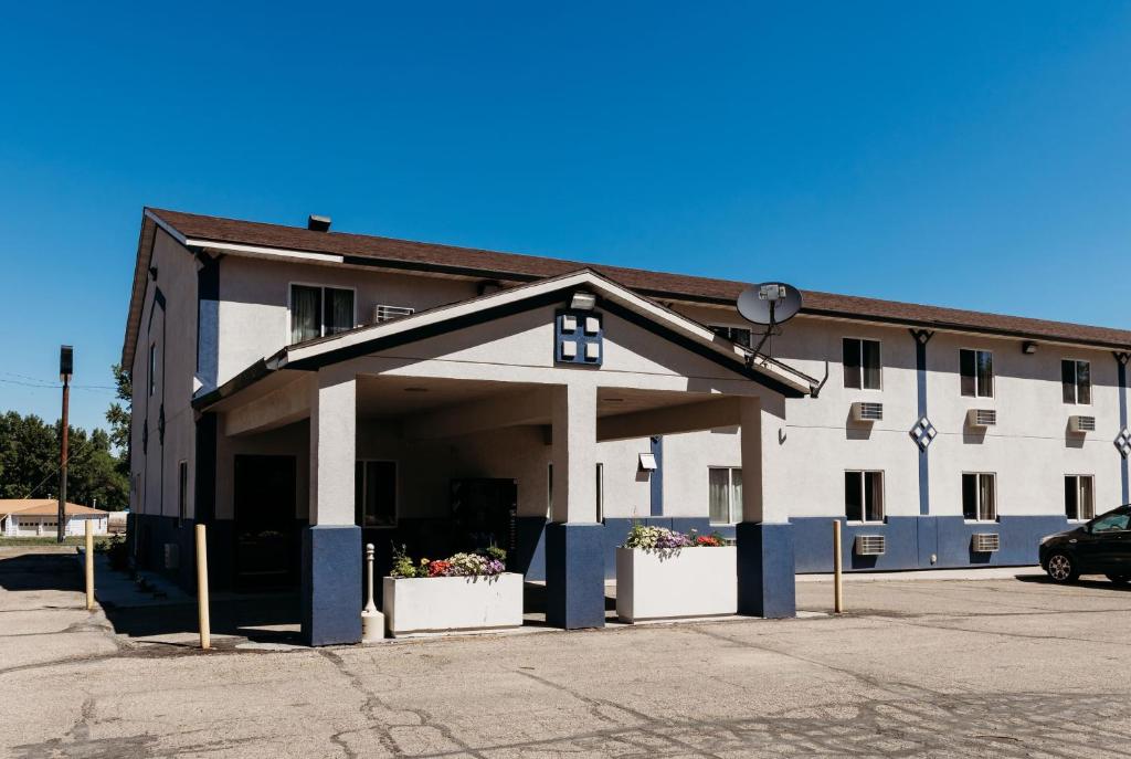a large white building with a parking lot at Travelodge by Wyndham Worland in Worland