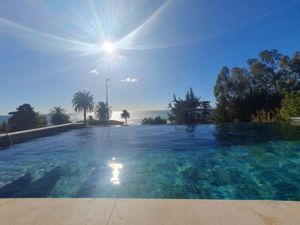 a large swimming pool with the sun in the sky at Villa Naussica in Saint-Raphaël