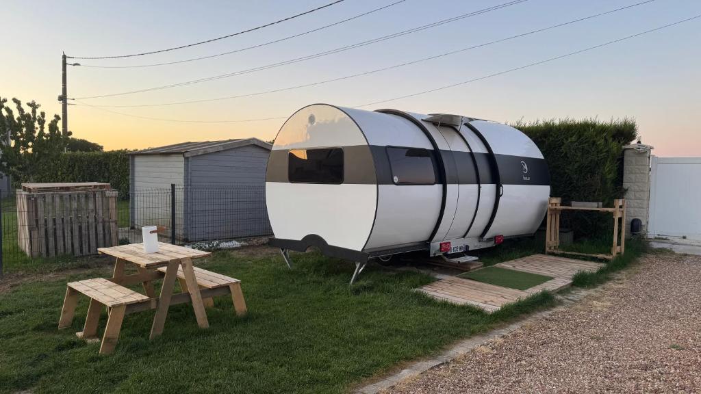 a caravan sitting in the grass next to a table at La caravane de Camille & Piscine in Soulaires