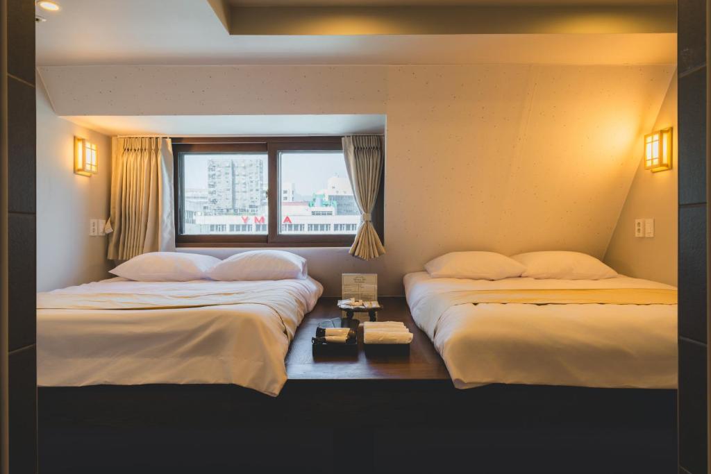 two beds in a hotel room with a window at Seoul101 Jongno in Seoul