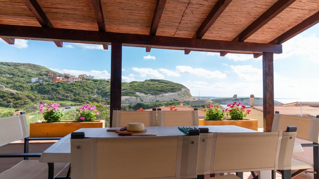 a patio with a table and chairs and a view at Golden Sunset - S'Archittu in S'archittu Cuglieri