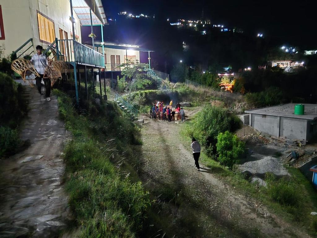 a group of people walking down a dirt road at night at Mountain Vibe Resort in Chamba