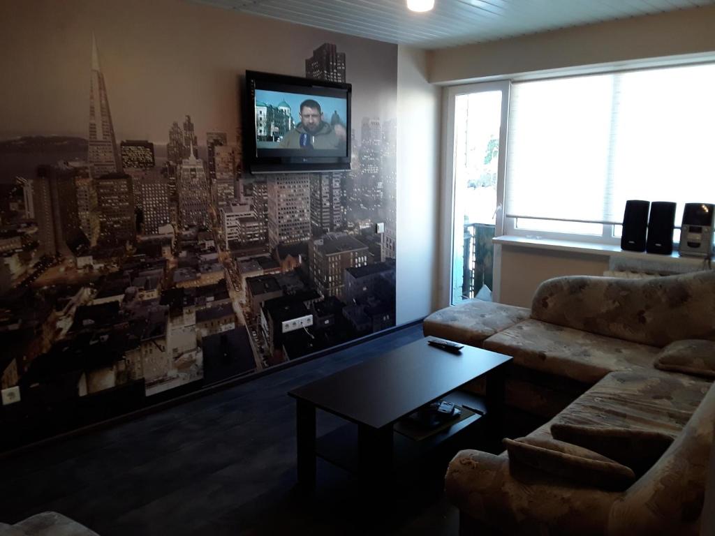 a living room with a couch and a tv on a wall at 2 room apartment 400m from sea in Liepāja