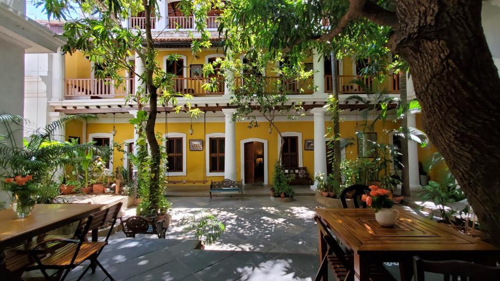 a courtyard with tables and chairs in front of a yellow building at Gratitude Heritage in Pondicherry